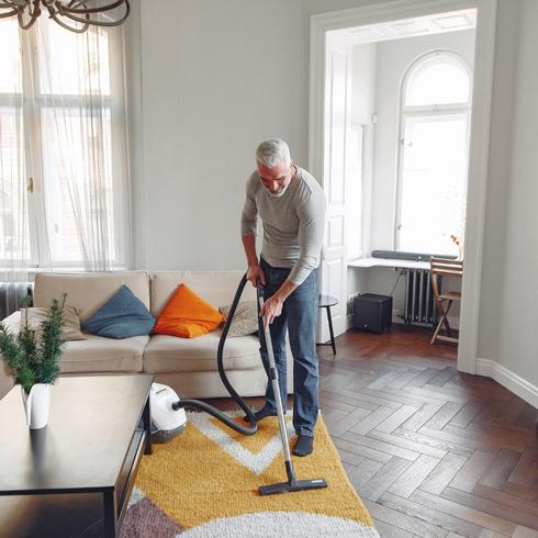 Senior man vacuuming floor