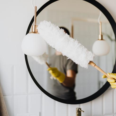 Woman dusting bathroom mirror