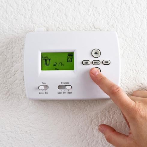 Person touching thermostat.