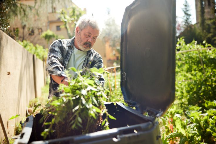 Man adding tree branches to compost bin 