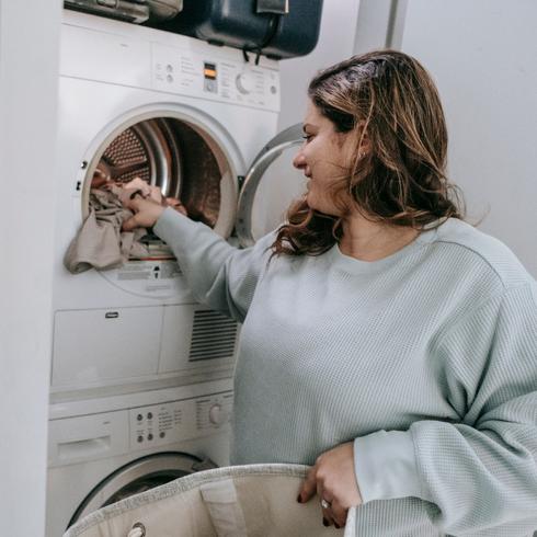 Person putting clothes into dryer.