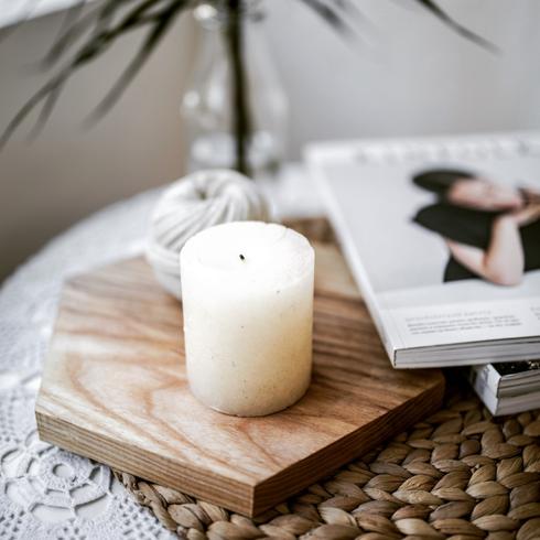 A candle on a coffee table with magazines