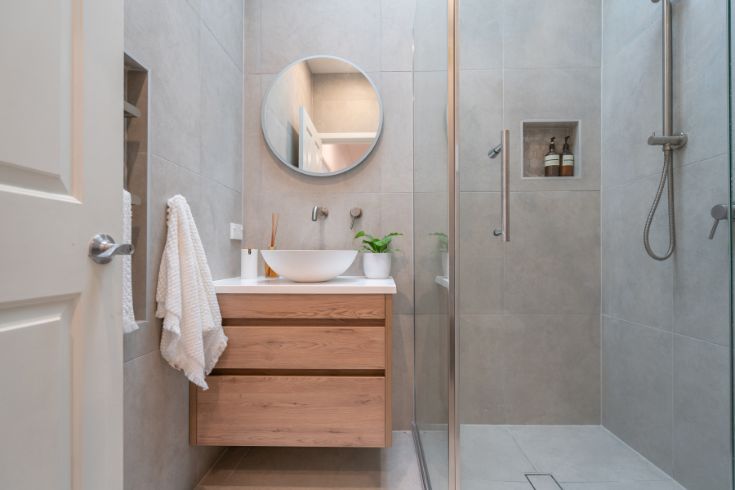 Modern bathroom with concrete walls and wooden vanity with drawers