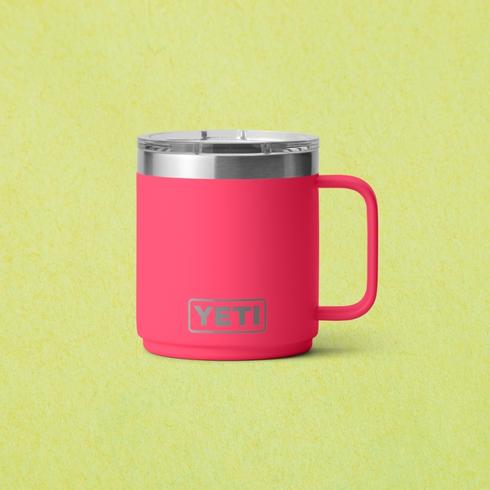 A bright pink mug in front of a green background