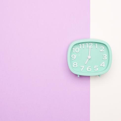 A blue clock on a purple and white background