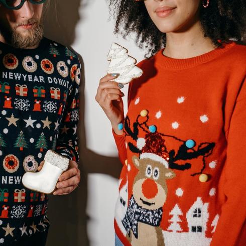 Two people holding christmas cookies