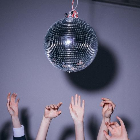 People raising hands under a disco ball.