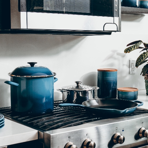 Assorted blue enamel cookware on the top of a stainless steel stove