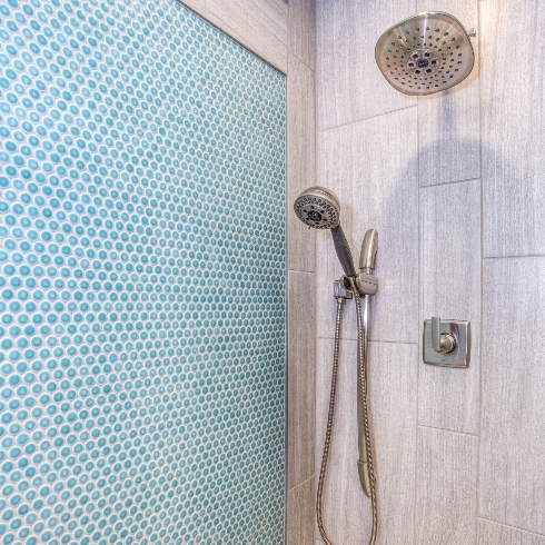 A shower with light blue tile and rain shower head