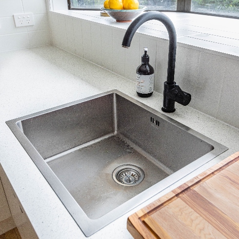 A stainless steel kitchen sink with black faucet and tap