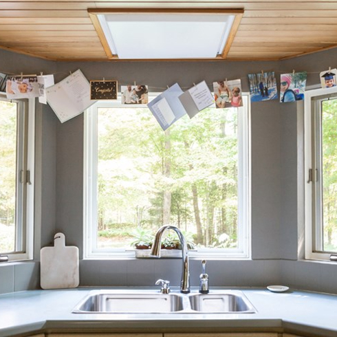 A kitchen sink with a bay window overlooking a forested area