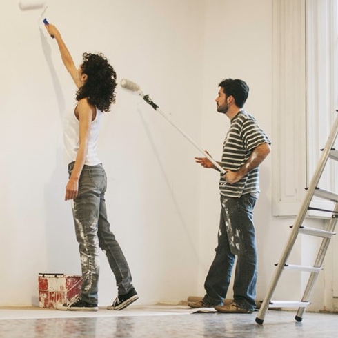 A couple painting a wall white