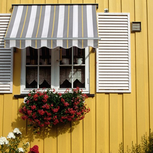 An awning over the window of a yellow house