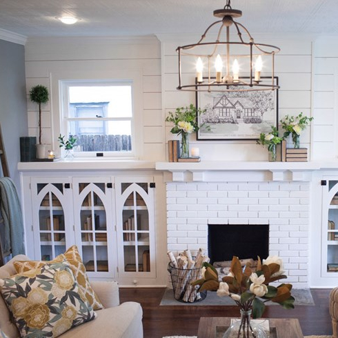 Shiplap-clad living room with mid-height shelves featuring vintage glass doors.