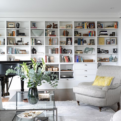 Modern-meets-traditional living room with wall of shelving and books.