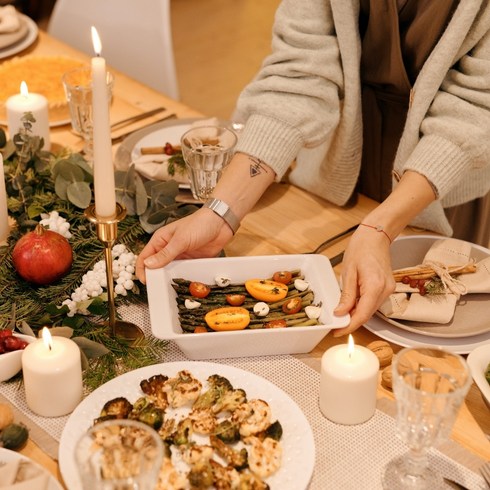 Person serving a meatless main dish during a holiday dinner party.