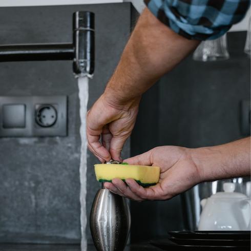 a person washing a yellow cleaning sponge