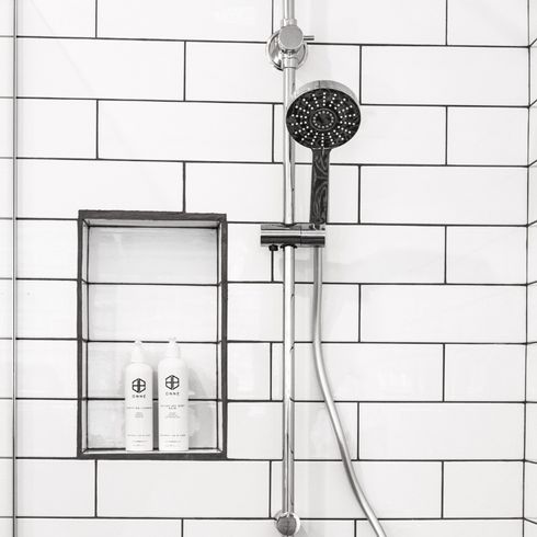 a shower with white tiles and a clean showerhead