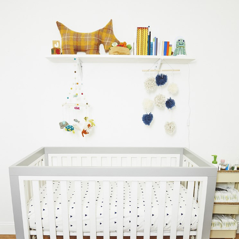 A white crib with a floating shelf above