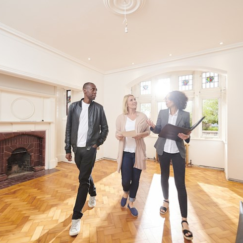 Couple and real estate agent in empty living room