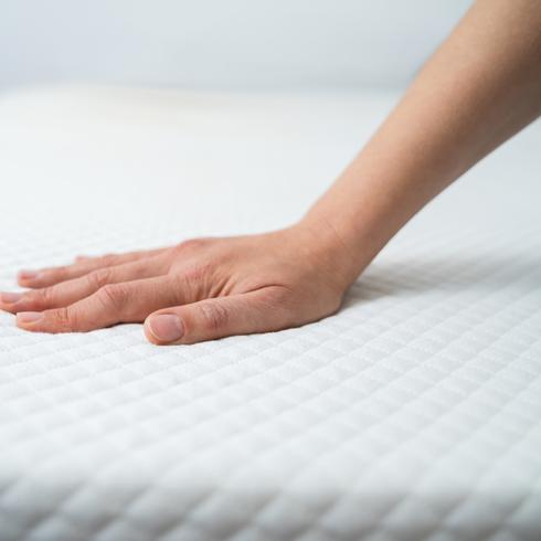 Person putting hand on mattress