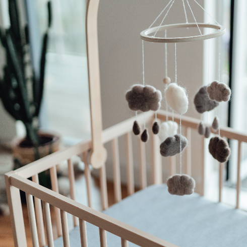 Stylish Scandinavian newborn baby nursery with natural wooden baby cot and handmade mobile hanging over it - stock photo