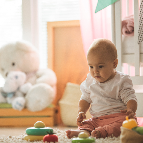 Adorable baby girl sitting at floor with toys - stock photo