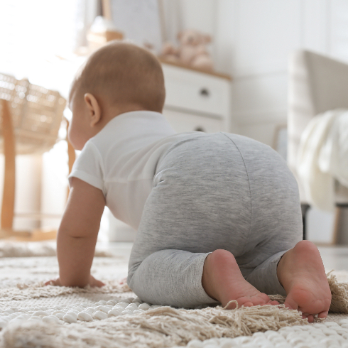 Cute baby crawling at home, focus on legs - stock photo