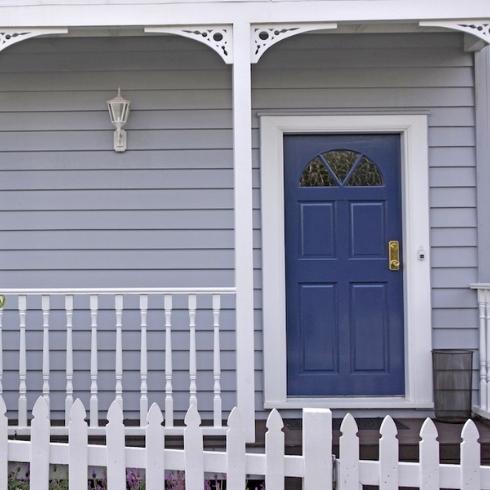 traditional blue villa exterior with entrance door and windows, balcony front yard, fence and a gate