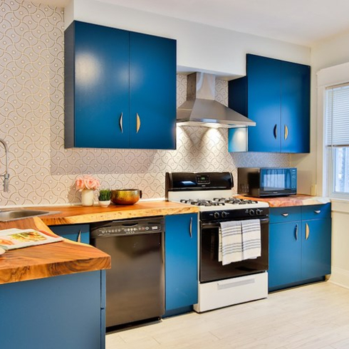 eclectic kitchen with blue cabinets, wood countertops and patterned wall