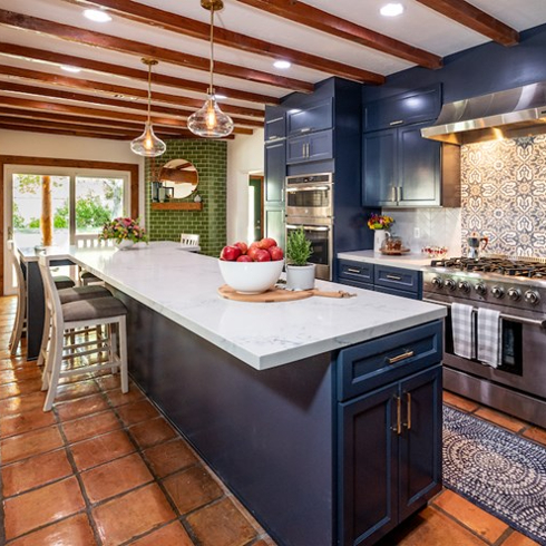 blue-cabinet kitchen with terra cotta floor, exposed beams and tile backspalsh