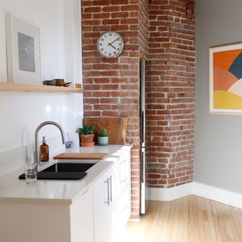 Small light-filled kitchen with sink and brick wall