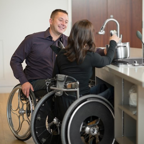 couple in wheelchairs at kitchen sink