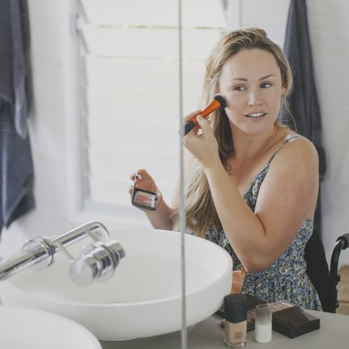 woman applying make up in her bathroom