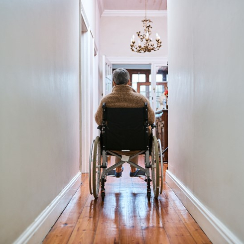 person in wheelchair in grey hallway