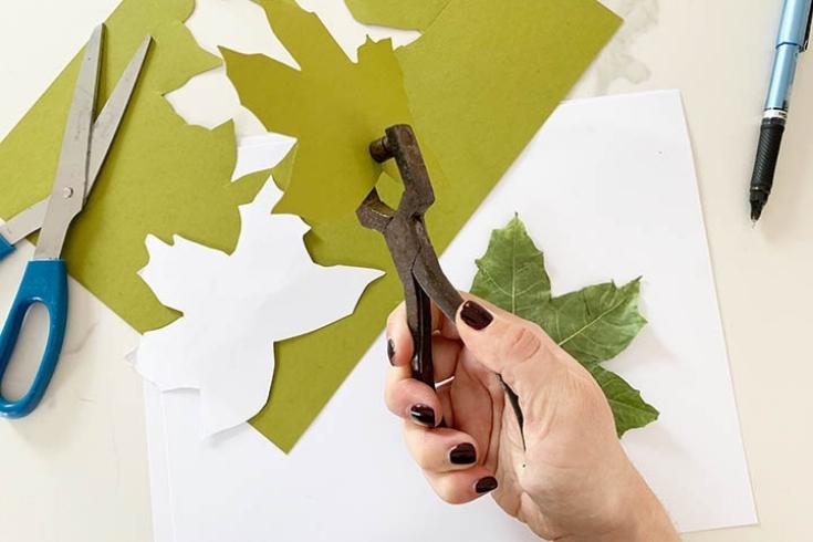 Person hole punching green leaf 