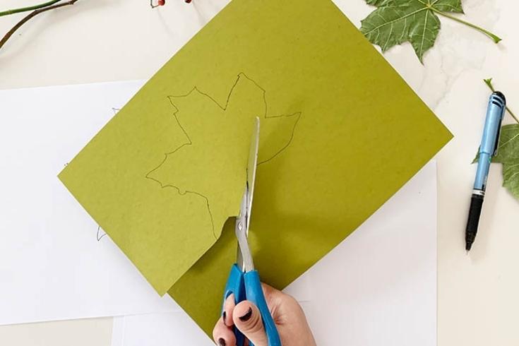 Person cutting a leaf on green piece of paper