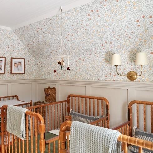 Nursery with two vintage wooden cribs and apple orchard wallpaper