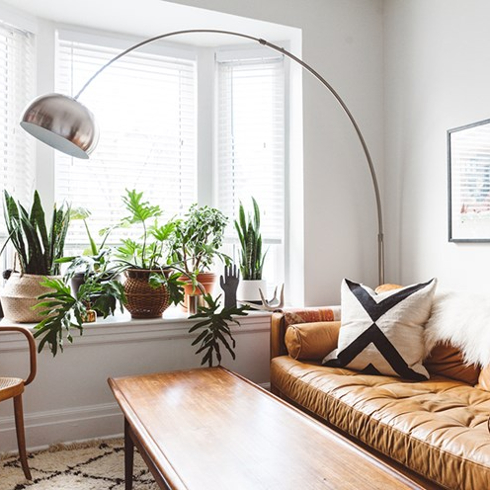 Bright, modern living room with a cognac leather couch. Several plants sit in a bright windowsill.