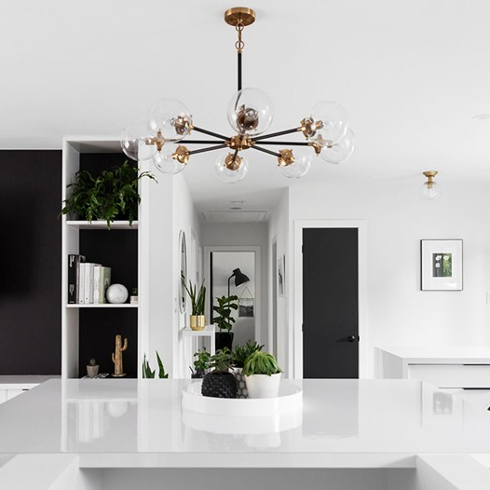 Minimalist, modern kitchen with small potted plants grouped together on clean, white counter.