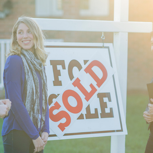 Couple in front of real estate sign