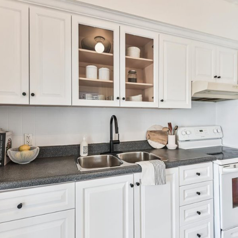 Kitchen with white painted cupboards, black countertops and a black faucet
