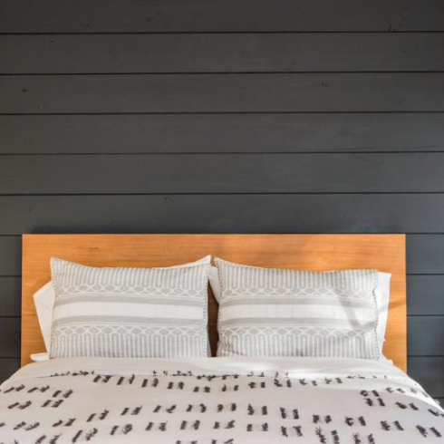 white bed and hanging light bulbs in bedroom with charcoal shiplap wall