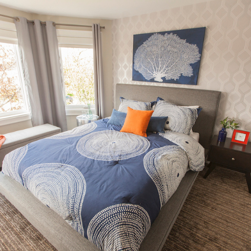 grey bedroom with blue bedding and art on wall