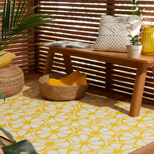 An outdoor yellow rug on wood balcony