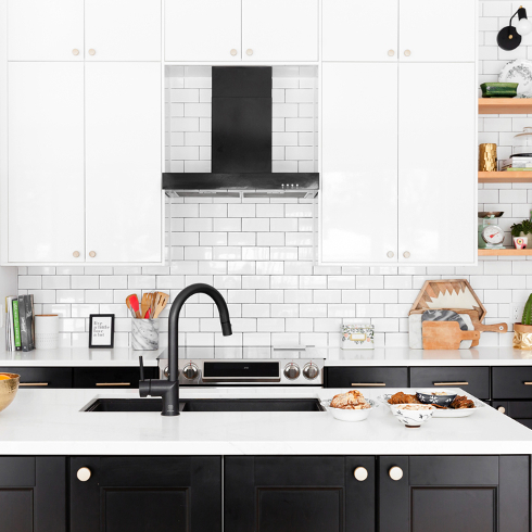 A modern kitchen with white tiles, a black kitchen island and a modern black faucet