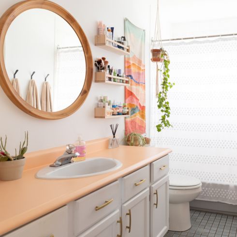 bright bathroom with small shelves on wall and peach-counter vanity