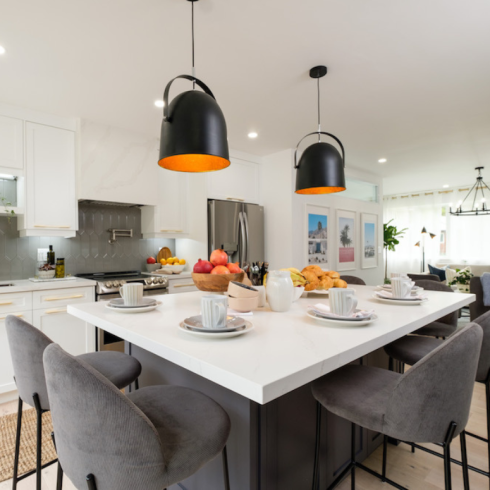 Large white kitchen island with black and brass pendant lights