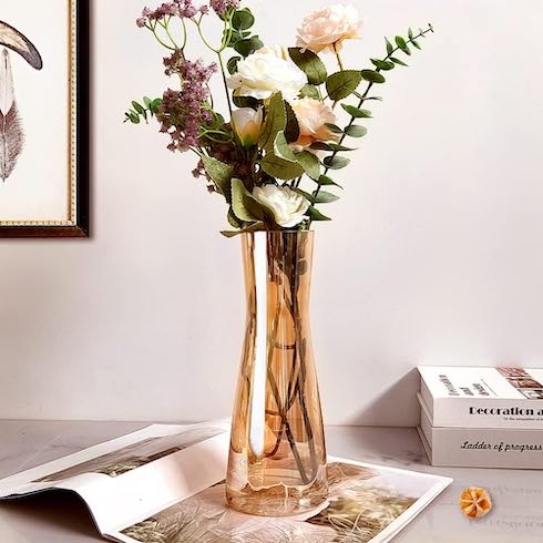 A mix of flowers in a delicate amber-glass vase on a counter