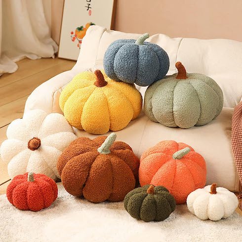 An array of colourful decorative fleece pumpkins sit on a soft white blanket